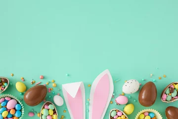 Foto op Canvas Easter sweets concept. Top view photo of easter bunny ears chocolate eggs with dragees and sprinkles on turquoise background with empty space © Goncharuk film