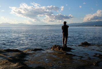 Spectacular scenery at the coast of Enoshima, Japan, with a lone fisherman standing at the edge to the water