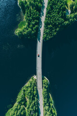 Aerial view of bridge road through blue lakes with green woods in Finland.