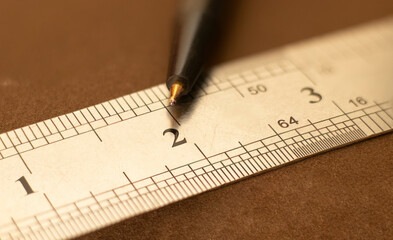 Close up of a stainless steel scale r ruler showing a Two inch point with pen, Selective focus,...