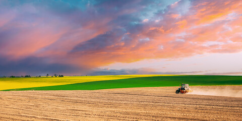 Tractor Plowing Field In Spring Season. Beginning Of Agricultural Spring Season. Amazing Bright Sky.