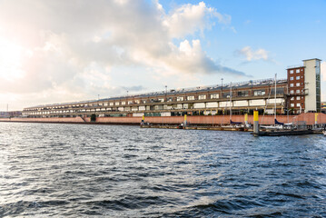 Old warehouse converted into retail and office spaces along a former harbour at sunset in summer
