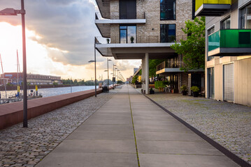 Harbourside footpath lined with new apartment buildings at sunset in summer