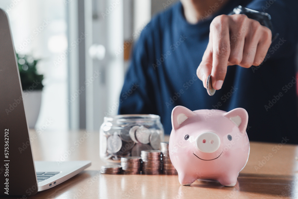 Wall mural hand putting coins in a piggy bank for save money and saving money concept.