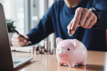 Obraz na płótnie Canvas Hand putting coins in a piggy bank for save money and Saving Money concept.