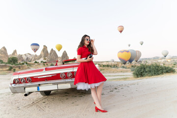 beautiful girl retro style posing near vintage red cabriolet car with old film camera  on...