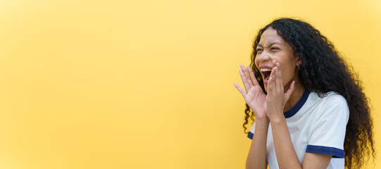 Cheerful black - American African woman yelling with hands close up on yellow background. Happy beautiful girl using hands at mount while screaming, woman speaking louder. Advertising concept.
