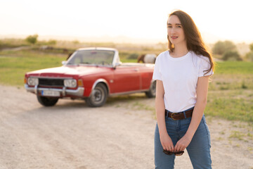 Fototapeta na wymiar beautiful girl in retro style posing near vintage red cabriolet car.