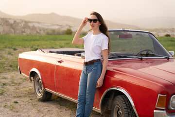 beautiful girl in retro style posing near vintage red cabriolet car.
