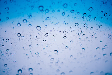 Naklejka na ściany i meble Blue water droplets and raindrops cling to the cool clear glass
