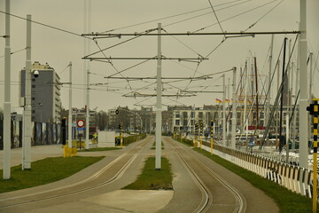 Fototapeta na wymiar Ligne du Tram de la Côte avec ses caténaires reliant toutes les cités balnéaires belges sous un ciel sombre à Ostende 