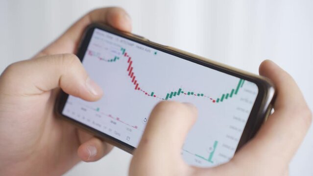 Close-up view of stock market and cryptocurrency charts from phone.
Close-up of man looking at stock market, stock, investment charts on phone.
