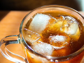 a glass of soda with ice on a wooden table
