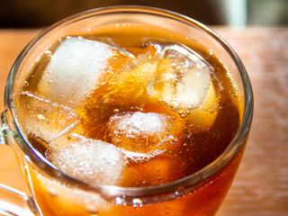 a glass of soda with ice on a wooden table