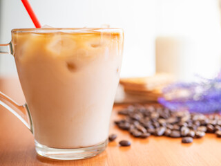 Ice coffee in a glass with milk with coffee beans on the table.Cookies and milk bottle.