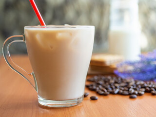 Ice coffee in a glass with milk with coffee beans on the table.Cookies and milk bottle.