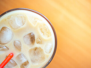 Ice coffee on a wood table with ice and red straw. Cold summer drink with red tube.Above close-up view flatlay
