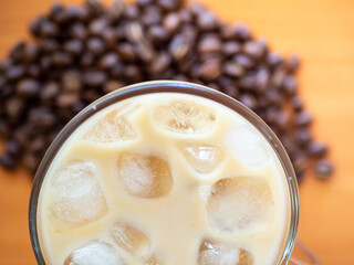 Ice coffee on a wood table with ice, coffe beans on background. Cold summer drink.Above close up view flatlay