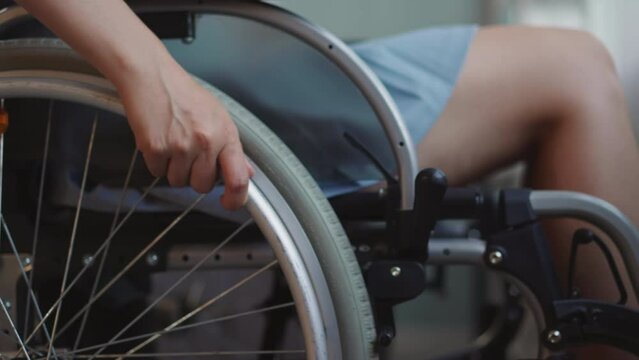 female patient with disability with spinal paralysis moves wheelchair in hospital. Woman controls modern medical equipment with hands closeup
