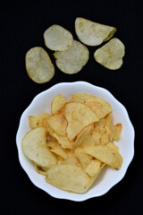 Potato chips in a white plate. Delicious pieces of chips. Salty fast food.