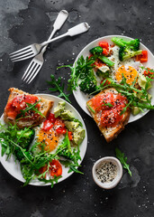 Delicious healthy breakfast - egg with vegetables, arugula salad and salmon cottage cheese toast on a dark background, top view