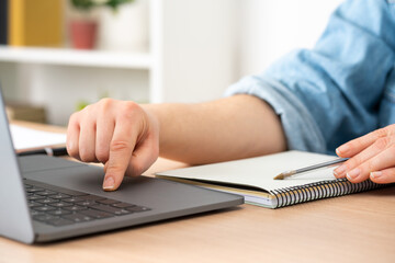 Close up of student girl hands comparing notes on laptop sitting on a desk at home