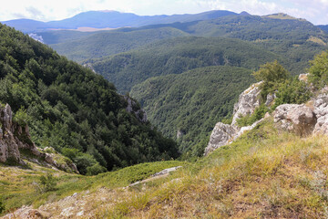 View from above into an Italian gorge in Abruzzo with mountains and forests in summer.