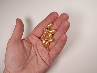 Cream serum in capsules for skin care on the palm on white background. Cosmetic products for skin, face care. Cosmetic products antiaging concept. Capsules with retinol, vitamin, hyaluron, collagen