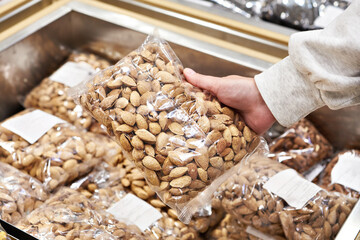 Nuts almonds in hands of woman buyer in store