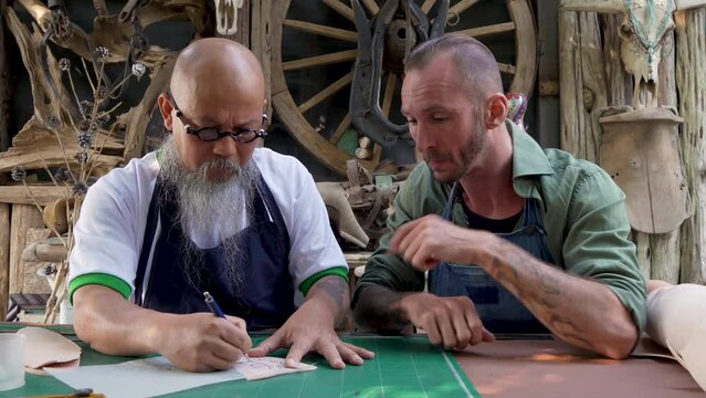 4K, technicians who are skilled in overlapping patterns pattern on cow leather, sitting here teaching drawing patterns on cowhide for young men who come study interested in handmade leather.
