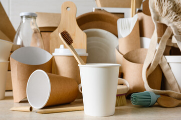 Concept of zero waste and environmental protection. Paper cup with a wooden toothbrush on the background of eco-friendly items. Selective focus on a toothbrush.