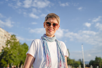 One mature woman caucasian female standing outdoor in sunny summer day wearing eyeglasses with short gray hair happy smile confident looking to the camera in parking lot copy space white t-shirt