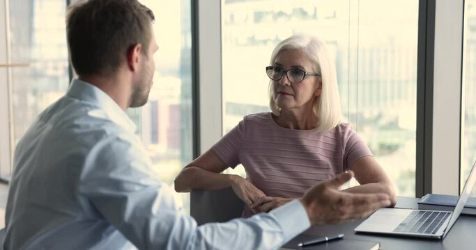 Older 60s and young 35s business partners, client and company employee talking meet in office, negotiate, planning future cooperation. Consult to customer, HR manager and applicant at job interview