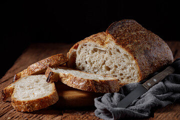 Rustic sourdough bread with cut slices on a wooden table. 