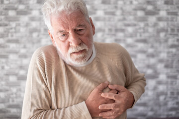 Old senior man with hands on chest from sudden pain, senior bearded male suffering from heart...