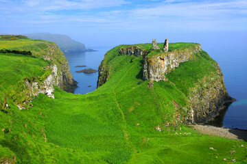 Ruins of the ancient Dunseverick Castle atop the green cliffs of the Causeway Coast, Northern...
