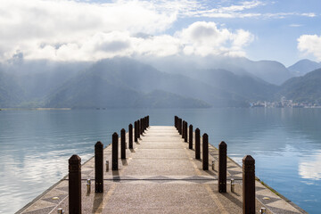 Fototapeta premium Large blue lake surrounded by mountains with pier in the morning at sun moon lake of Taiwan