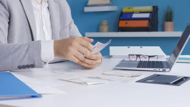 Office worker calculates household budget in his room and gets angry at exorbitant spending bill prices.