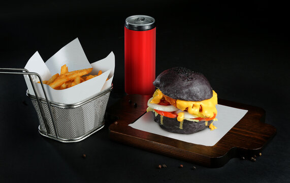 delicious Black chicken color burger served on wooden tray black background with soft drink and Potato Fries