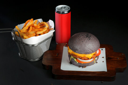 delicious black color venison deer meat  burger served on wooden tray black background with soft drink and Potato Fries
