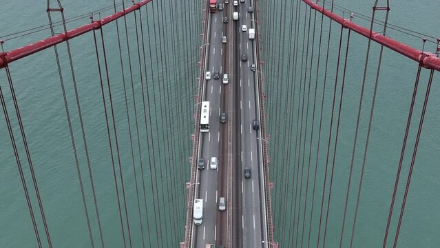 Traffic on The 25 April bridge (Ponte 25 de Abril) located in Lisbon, Portugal, crossing the Tagus river. Drone. 4k
