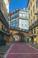 Narrow street with pink road and bridge in Lisbon, Portugal