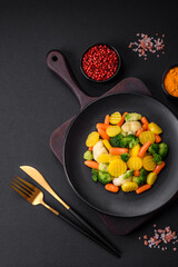 Delicious fresh vegetables steamed carrots, broccoli, cauliflower on a black plate