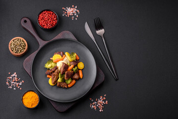 Delicious fresh beef and vegetables carrots, broccoli, cauliflower on a black plate