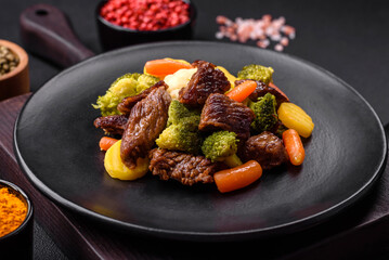 Delicious fresh beef and vegetables carrots, broccoli, cauliflower on a black plate