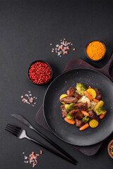 Delicious fresh beef and vegetables carrots, broccoli, cauliflower on a black plate