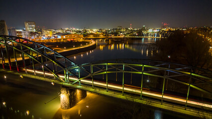 Light trail of a train on the bridge over the river in the city at night