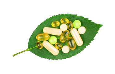 Variety of dietary supplement pills on fresh green leaf isolated on transparent background, top...