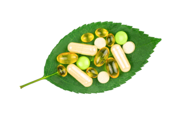 Variety of dietary supplement pills on fresh green leaf isolated on transparent background, top view. Alternative medicine concept
