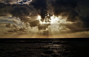 The sun in the clouds before sunset at sea